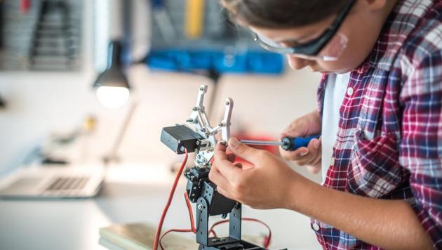 Young girl fixing a robot arm in a workshop.(Getty Images)