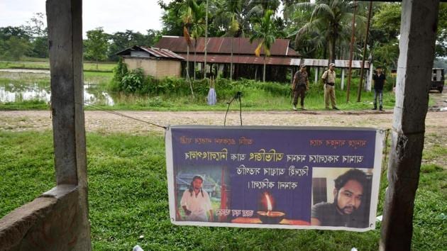 Security personnel near a commemorative poster for two men, Abhijit Nath and Nilotpal Das, who were lynched nearby in Panjuri Kachari village, in Karbi Anglong district some 180km from Guwahati on July 10.(AFP Photo)