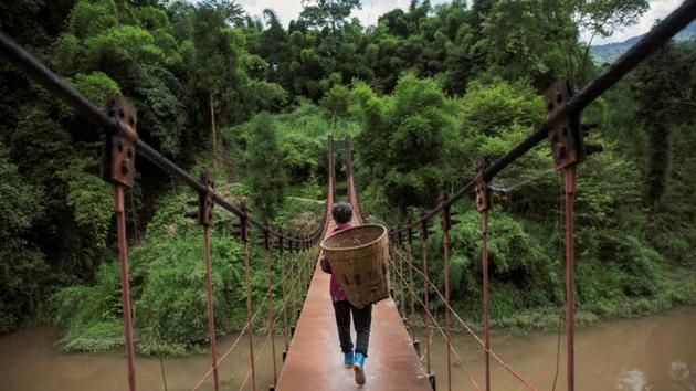 A villager carries a basket over a suspension bridge on the Zhougong River. China’s official hydropower capacity was about 340 GW at the end of June and around a third of that is considered small hydropower, projects of less than 50 MW. China’s overall power capacity, including coal and nuclear plants, is 1,740 GW. (Damir Sagolj / REUTERS)