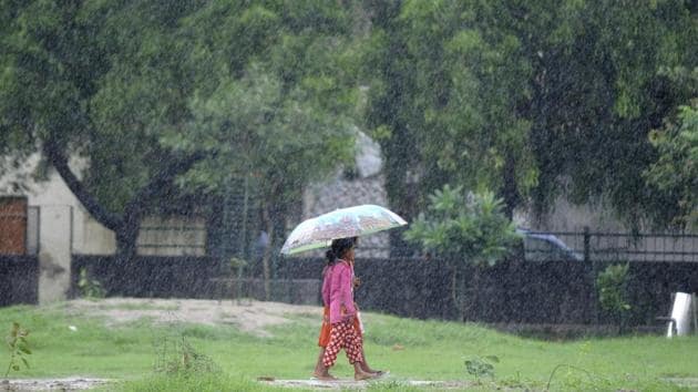 Children walk in the rain under in Noida on Sunday. Heavy rains lashed parts of northern India over the weekend.(Sunil Ghosh/HT Photo)