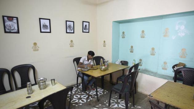 The logo for ‘vaishno dhaba’ features Chalittar Mukhiya, the owner, who started the dhaba in the 1990s. The inside walls have stencil art with photos of his father and him as a young man selling food on a cart; a chalkboard as a menu. Choudhury said he wanted a nostalgia-driven design, inspired by vintage coffee house aesthetics, which remained functional for Mukhiya and his clients. (Burhaan Kinu / HT Photo) 