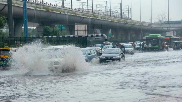 Motorists wading through a waterlogged street following heavy rain in Noida on Saturday. (PTI) Motorists wading through a waterlogged street following heavy rain in Noida on Saturday. (PTI)