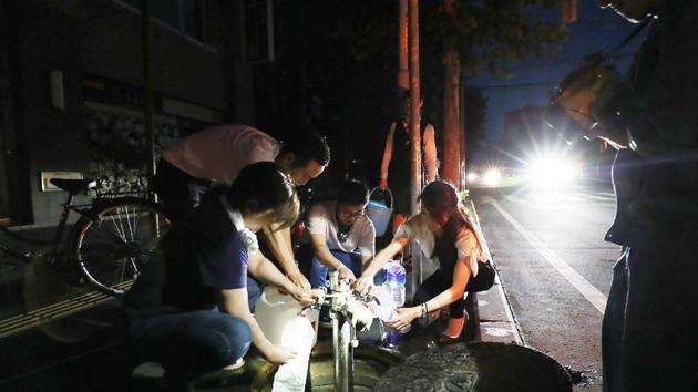 Earthquake-affected residents fill water bottles as an electrical blackout shrouds the shopping district in Sapporo on September 6, 2018, after an earthquake hit the northern Japanese island of Hokkaido. (AFP) Earthquake-affected residents fill water bottles as an electrical blackout shrouds the shopping district in Sapporo on September 6, 2018, after an earthquake hit the northern Japanese island of Hokkaido. (AFP)
