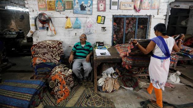 Bharat Lal (L) who lost his job as a powerloom operator at a weaving factory earlier this year now works as a clerk in a factory in Panipat. "It's really getting very difficult for us to survive now, I have a son who is still in school and I'm really worried about his future. I want to save as much as I can for his studies," Lal said. (Adnan Abidi / REUTERS)