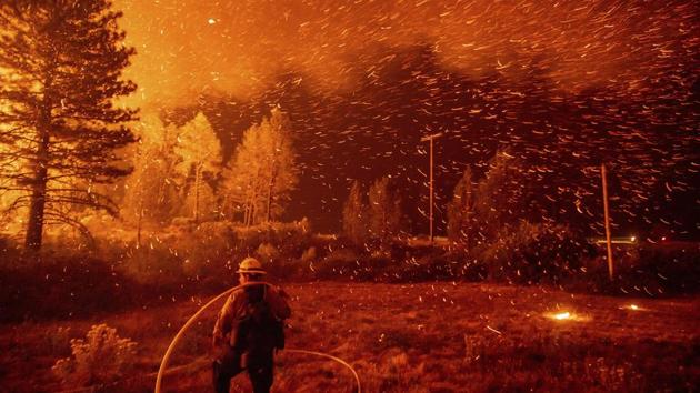 Embers fly above a firefighter as he works to control a backfire as the Delta Fire burns in the Shasta-Trinity National Forest, California. (Noah Berger / AP) Embers fly above a firefighter as he works to control a backfire as the Delta Fire burns in the Shasta-Trinity National Forest, California. (Noah Berger / AP)