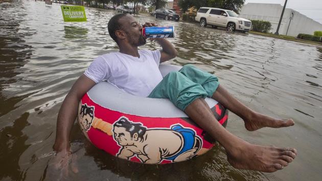 Johnny Jones drinks a beer while floating and watching a single-file line of drivers make their way down Broadway Boulevard after heavy rains caused substantial street flooding in Galveston, Texas. (Stuart Villanueva / The Galveston County Daily News via AP) Johnny Jones drinks a beer while floating and watching a single-file line of drivers make their way down Broadway Boulevard after heavy rains caused substantial street flooding in Galveston, Texas. (Stuart Villanueva / The Galveston County Daily News via AP)