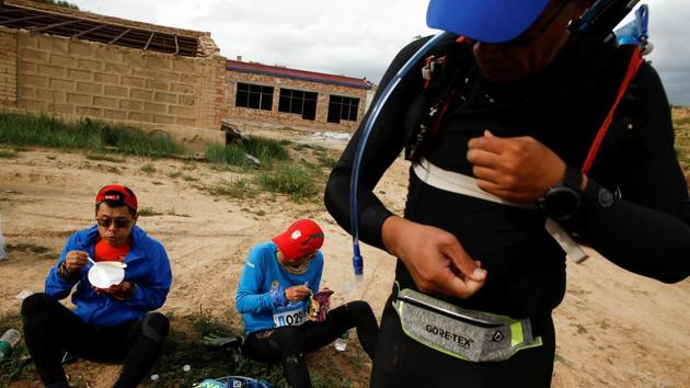 Participants eat cup noodles at a checkpoint. Beijing has called for 1,000 such towns by 2020 in a drive to develop sustainable industries in the hinterlands, but doubts remain over the pay off. The benefits to Longyangxia, for instance, are still mostly aspirational. The town centre is still a ring of empty buildings, the market street a pile of rubble. (Thomas Peter / REUTERS) Participants eat cup noodles at a checkpoint. Beijing has called for 1,000 such towns by 2020 in a drive to develop sustainable industries in the hinterlands, but doubts remain over the pay off. The benefits to Longyangxia, for instance, are still mostly aspirational. The town centre is still a ring of empty buildings, the market street a pile of rubble. (Thomas Peter / REUTERS)