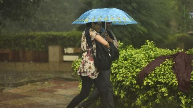 Two women walk under an umbrella at Janpath in New Delhi on Thursday. (Burhaan Kinu/ HT Photo)(Burhaan Kinu/HT PHOTO)