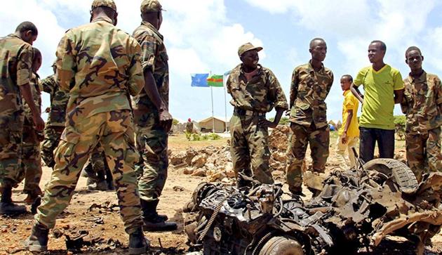 Jubaland forces and Somali residents stand near the site of a suicide car bomb attack near a military training base in the port town Kismayu.(Representative Image/Reuters Photo)