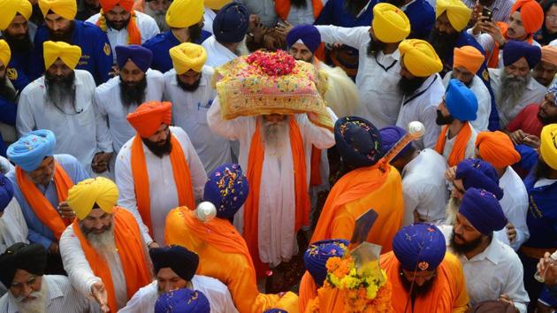 Sikh priest Giani Jagtar Singh (C) carries the Guru Granth Sahib, the central religious text of Sikhism during a religious procession from Gurudwara Ramsar to Akal Takht Sahib to mark the 414th anniversary of the installation of the Guru Granth Sahib at the Golden Temple in Amritsar on Monday. (Narinder Nanu / AFP) Sikh priest Giani Jagtar Singh (C) carries the Guru Granth Sahib, the central religious text of Sikhism during a religious procession from Gurudwara Ramsar to Akal Takht Sahib to mark the 414th anniversary of the installation of the Guru Granth Sahib at the Golden Temple in Amritsar on Monday. (Narinder Nanu / AFP)
