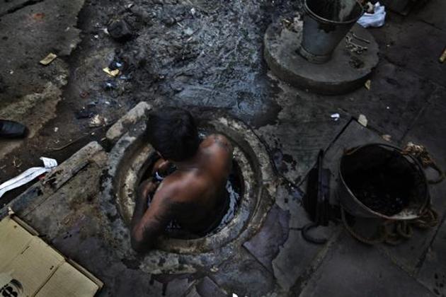 A file picture of a municipal worker attempts to unblock a sewer in New Delhi. Casual workers who endanger their lives for as little as <span class='webrupee'>?</span>300 to clean septic tanks don’t seem to be a priority either with the law enforcement agencies or politicians. This is a blot on the record of a country running the largest public cleanliness programme in the world(Raj K Raj/Hindustan Times)