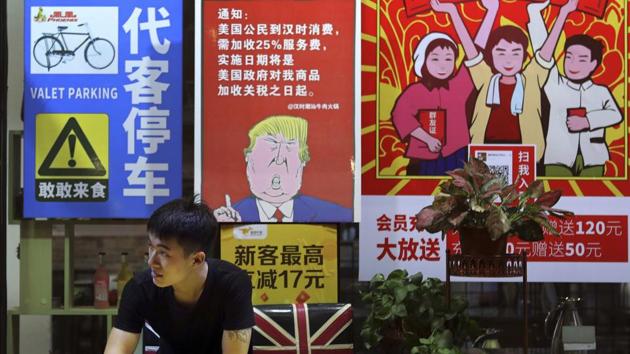 A man stands near a poster depicting a mural of US President Donald Trump, on display outside a restaurant in Guangzhou in south China's Guangdong province. (AP File Photo) A man stands near a poster depicting a mural of US President Donald Trump, on display outside a restaurant in Guangzhou in south China's Guangdong province. (AP File Photo)