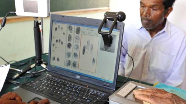 A man looks on as another puts his hand on a 'Slap Pad' for recording of fingerprints during the data collecting process for a pilot project of UIDAI.(AFP File Photo)