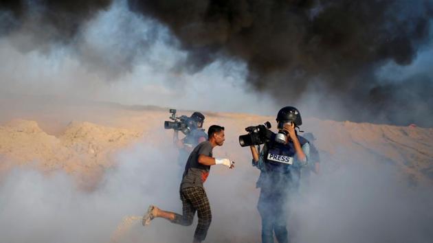 Cameramen film as a Palestinian demonstrator reacts to tear gas fired by Israeli troops during a protest calling for lifting the Israeli blockade on Gaza, on a beach near the maritime border with Israel, in the northern Gaza Strip. (Mohammed Salem / REUTERS)
