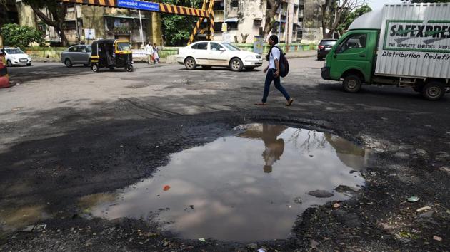 A girl walks past a pothole at Kalmboli in Navi Mumbai. Potholes are so common that a campaign is under way to have Mumbai featured in the Guinness Book of Records as the city with the most potholes. Navin Lade, a resident, claims to have recorded more than 27,000 holes on his website, although local officials dispute his findings. (Bachchan Kumar / HT File)