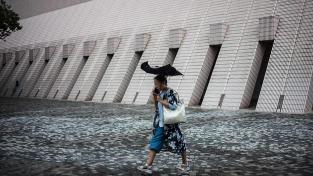 A woman uses an umbrella as she walks along a promenade that runs along Victoria Harbour in Hong Kong. (Anthony Wallace / AFP)