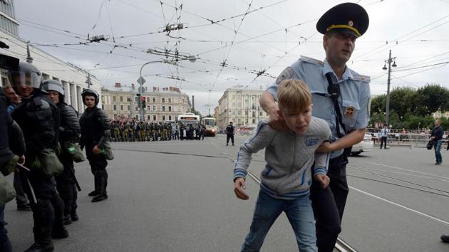 Russian police escorts a youth during a protest rally against planned increases to the nationwide pension age in Saint Petersburg. (Olga Maltseva / AFP)