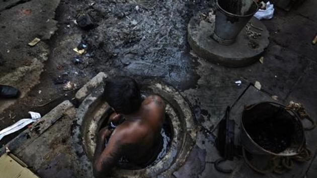 Municipal worker attempts to unblock a sewer overflowing with human excreta in New Delhi on October 7, 2009(HT File Photo)