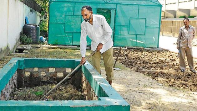 Many schools in the tricity have taken to composting their green waste. A gardener rakes leaves into one such pit at Shivalik Public School. (HT Photo) Many schools in the tricity have taken to composting their green waste. A gardener rakes leaves into one such pit at Shivalik Public School. (HT Photo)