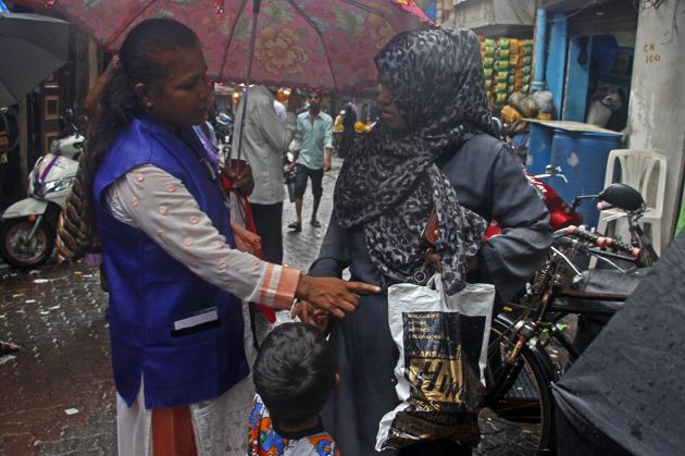 A BMC official makes a local women understand the harmful effect of using plastic bags at Keshavji Nayak road near JJ Hospital in Mumbai.(HT PHOTO)