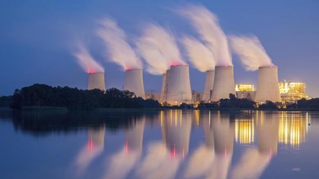 Steam and cooling towers of a lignite power plant are reflected in a pond in Peitz, eastern Germany. (Patrick Pleul / dpa via AP)