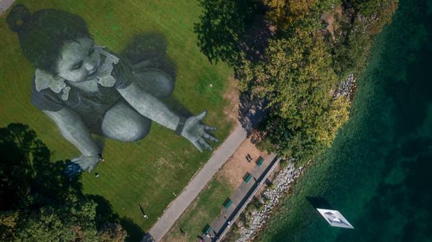 This aerial view shows French artist Saype’s giant land art fresco representing a little girl dropping an origami boat into Lake Geneva that he painted to support the cause of the NGO SOS Mediterranee in Geneva, Switzerland. The giant fresco covering 5,000 sq. mtrs was produced with biodegradable paints from natural pigments. (Fabrice Coffrini / AFP)