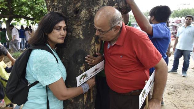 Environmentally conscious citizens protest against cutting of trees by hugging them.(Sanjeev Verma/HT PHOTO)
