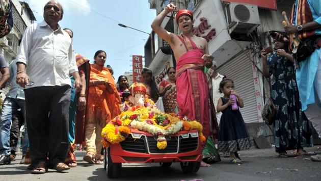 Milind Sampgaonkar and his family during their Ganesh visarjan on Sunday at Kumthekar road. Their Ganesh idol was driven in a toy car during the procession.  (ht photo) 