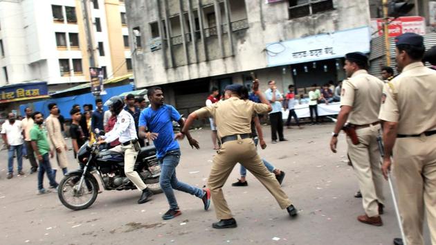 Police official chase a man during the Ganesh immersion procession on Tilak road on Sunday. (HT Photo) 