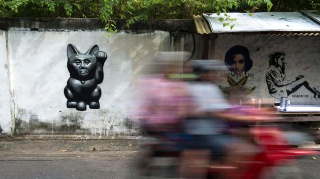 Graffiti of Thailand’s junta chief depicted as ‘a lucky cat’ with paw raised to rake in money (L), with the work of London artist ‘Dotmaster’ (2nd R). “Street art has a fast life... you can cover it with paint but once it is on social media, it stays,” said Apinan Poshyananda, artistic director of the Bangkok Art Biennale which debuts next month and will feature other street artists. (Romeo Gacad / AFP) Graffiti of Thailand’s junta chief depicted as ‘a lucky cat’ with paw raised to rake in money (L), with the work of London artist ‘Dotmaster’ (2nd R). “Street art has a fast life... you can cover it with paint but once it is on social media, it stays,” said Apinan Poshyananda, artistic director of the Bangkok Art Biennale which debuts next month and will feature other street artists. (Romeo Gacad / AFP)