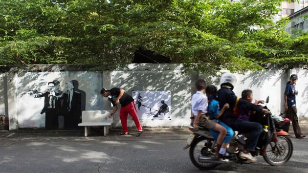 Headache works on a new graffiti next to his caricature of Kim Jong-un and Donald Trump pointing a gun. Kawita is part of a wider artistic awakening in Thailand, whose painters, sculptors and performers traditionally took inspiration from the establishment, but who are now confronting different themes. The launch of the Biennale will display work by headline names such as Marina Abramovic and the late Jean-Michel Basquiat. (Romeo Gacad / AFP) Headache works on a new graffiti next to his caricature of Kim Jong-un and Donald Trump pointing a gun. Kawita is part of a wider artistic awakening in Thailand, whose painters, sculptors and performers traditionally took inspiration from the establishment, but who are now confronting different themes. The launch of the Biennale will display work by headline names such as Marina Abramovic and the late Jean-Michel Basquiat. (Romeo Gacad / AFP)