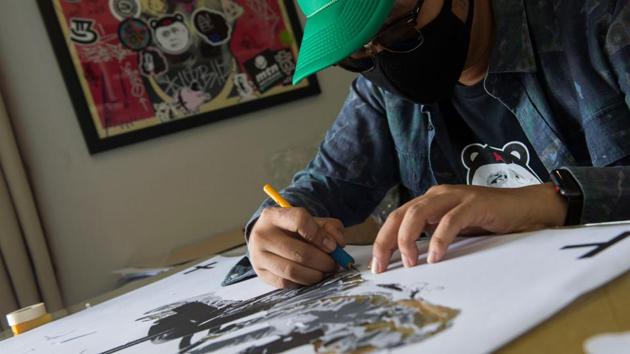A Thai artist who goes by the name of ‘Headache Stencil’ works in his studio in Bangkok. Dubbed Thailand’s “Banksy”, Headache -- whose nickname alludes to the pain he hopes to inflict on the mighty -- catapulted to fame in January with a piece skewering junta number two Prawit Wongsuwan, who was struggling to explain his collection of undeclared luxury watches. (Romeo Gacad / AFP) A Thai artist who goes by the name of ‘Headache Stencil’ works in his studio in Bangkok. Dubbed Thailand’s “Banksy”, Headache -- whose nickname alludes to the pain he hopes to inflict on the mighty -- catapulted to fame in January with a piece skewering junta number two Prawit Wongsuwan, who was struggling to explain his collection of undeclared luxury watches. (Romeo Gacad / AFP)
