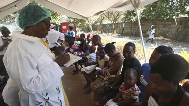 A health worker screens mothers and their children for symptoms of cholera in a quarantine area. Widespread unemployment has forced some to ignore cholera warnings. For days, police have battled to clear Harare’s streets of thousands of people hustling as vendors, saying it will help reduce the disease spreading. Some now play cat-and-mouse with police, wary of arrests and confiscations. Others have taken to vending at night. (Tsvangirayi Mukwazhi / AP) A health worker screens mothers and their children for symptoms of cholera in a quarantine area. Widespread unemployment has forced some to ignore cholera warnings. For days, police have battled to clear Harare’s streets of thousands of people hustling as vendors, saying it will help reduce the disease spreading. Some now play cat-and-mouse with police, wary of arrests and confiscations. Others have taken to vending at night. (Tsvangirayi Mukwazhi / AP)