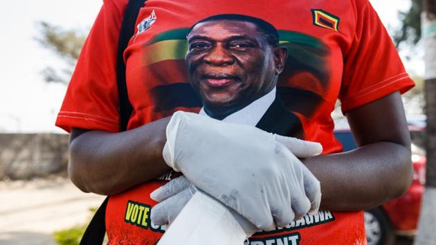 A supporter of Zimbabwe’s ruling party wears latex gloves as president Emmerson Mnangagwa visits a medical camp for people suffering from cholera in Harare. The outbreak has prompted the government to declare a public health emergency. These signs are not encouraging. Inflation has spiked. Mnangagwa, who took office after the fall of Robert Mugabe and for a while sent hopes soaring, now spends his time vowing to fight a “medieval” disease. (Jekesai Njikizana / AFP) A supporter of Zimbabwe’s ruling party wears latex gloves as president Emmerson Mnangagwa visits a medical camp for people suffering from cholera in Harare. The outbreak has prompted the government to declare a public health emergency. These signs are not encouraging. Inflation has spiked. Mnangagwa, who took office after the fall of Robert Mugabe and for a while sent hopes soaring, now spends his time vowing to fight a “medieval” disease. (Jekesai Njikizana / AFP)