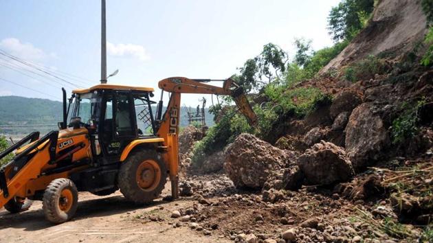 A JCB machine clears debris from a road after a landslide took place on the outskirts of Jammu on Tuesday. Thirty people, including women and children were rescued in Jammu and Kashmir during a flash flood in Kathua district on Monday. These people were marooned in different parts of the district following heavy rains. (Nitin Kanotra/HT)