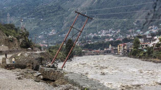 An electric pole on the bank of the swollen River Beas stands tilted after incessant rains, in Kullu, Himachal Pradesh on Tuesday.(PTI Photo)