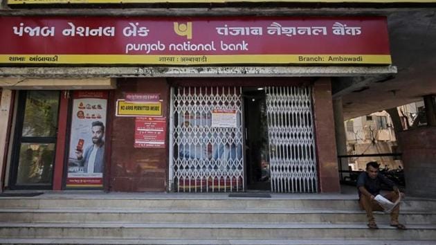 A man reads a newspaper outside a branch of Punjab National Bank (PNB) in Ahmedabad on March 20.(Reuters)