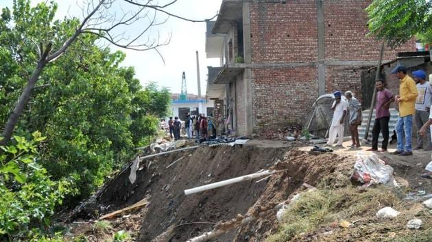Residents gathered at the site where a lane in front of their houses was washed away by a seasonal rivulet during the Monday’s heavy rain at Mauli Baidwan village in Sector 80, Mohali. (HT Photo) Residents gathered at the site where a lane in front of their houses was washed away by a seasonal rivulet during the Monday’s heavy rain at Mauli Baidwan village in Sector 80, Mohali. (HT Photo)