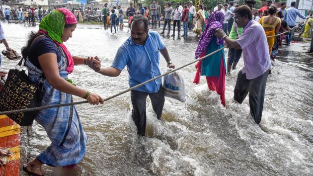 Citizens helped women residents cross the street that was flooded after a wall of Mutha canal collapsed near Dandekar bridge by using a rope on Thursday. (SANKET WANKHADE/HT PHOTO) Citizens helped women residents cross the street that was flooded after a wall of Mutha canal collapsed near Dandekar bridge by using a rope on Thursday. (SANKET WANKHADE/HT PHOTO)