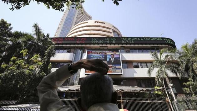 A man looks at a screen across the road displaying the Sensex on the facade of the Bombay Stock Exchange (BSE) building in Mumbai.(Reuters)
