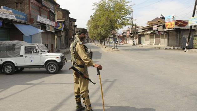 Paramilitary soldiers stand guard near a temporary barricade during a shutdown in downtown area of Srinagar on Friday.(Waseem Andrabi /HT Photo)