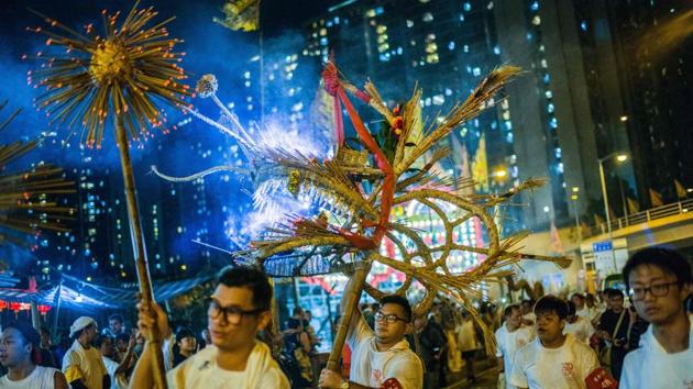 Performers carry an ornate straw-stuffed dragon stuck with hundreds of incense sticks in Pok Fu Lam village in Hong Kong as part of a traditional celebration of mid-autumn festival. (Anthony Wallace / AFP) Performers carry an ornate straw-stuffed dragon stuck with hundreds of incense sticks in Pok Fu Lam village in Hong Kong as part of a traditional celebration of mid-autumn festival. (Anthony Wallace / AFP)