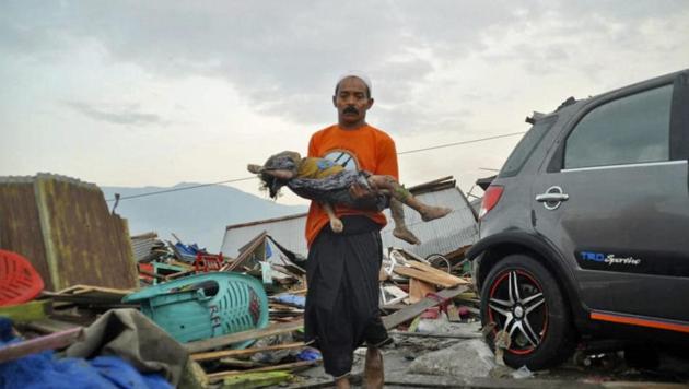 A man carries the body of a child who was killed in the tsunami in Palu, Central Sulawesi, Indonesia.(AP Photo)