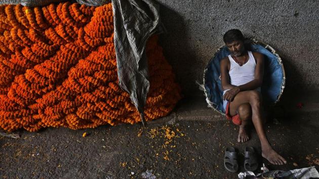 A head-load worker rests on his basket beside a pile of marigold flowers at a wholesale market in Kolkata, West Bengal. (Bikas Das / AP)