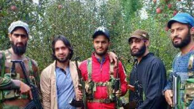 Adil Bashir, who is wearing a red jacket in this photo, is pictured standing with alleged Hizbul Hizbul Mujahideen militants. (Photo from social media) Adil Bashir, who is wearing a red jacket in this photo, is pictured standing with alleged Hizbul Hizbul Mujahideen militants. (Photo from social media)