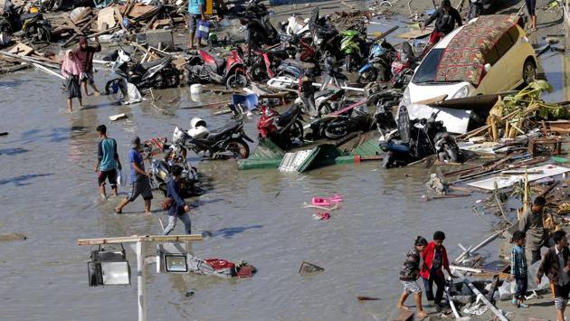 People survey outside the flooded shopping mall which was damaged during the twin disasters. A mass burial of earthquake and tsunami victims is being prepared in the hard-hit city Monday. The grave being dug in Palu for 300 victims will be 10 meters by 100 meters. (AP) People survey outside the flooded shopping mall which was damaged during the twin disasters. A mass burial of earthquake and tsunami victims is being prepared in the hard-hit city Monday. The grave being dug in Palu for 300 victims will be 10 meters by 100 meters. (AP)