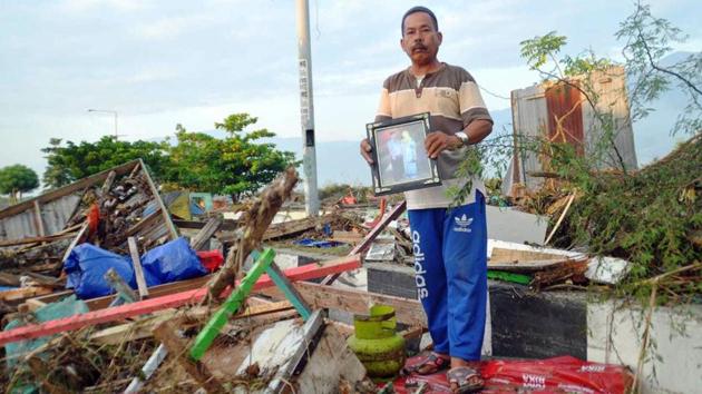 A man holds a family picture retrieved from a damaged house following a massive earthquake and tsunami. Of particular concern is Donggala, a region of 300,000 people north of Palu and close to the epicentre of the quake, and two other districts, which had been cut off from communications since Friday. (Rifki / AP) A man holds a family picture retrieved from a damaged house following a massive earthquake and tsunami. Of particular concern is Donggala, a region of 300,000 people north of Palu and close to the epicentre of the quake, and two other districts, which had been cut off from communications since Friday. (Rifki / AP)