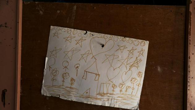 A drawing of a house hangs on the wall of an empty hut after its inhabitants had left. The houses are well-equipped and clean, in contrast to the fiber-board walls and open sewage gutters at the campsite. Still, the family said they felt unsettled and had already heard neighbours express reservations about their arrival. (Susana Vera / REUTERS) 