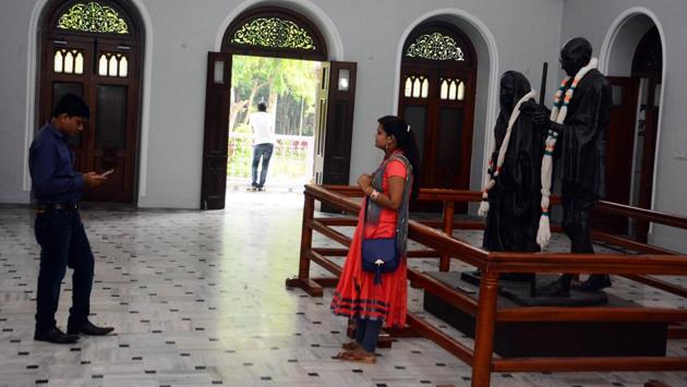 People take pictures near the Gandhi statue at Aga Khan Palace. (SHANKAR NARAYAN/HT PHOTO)