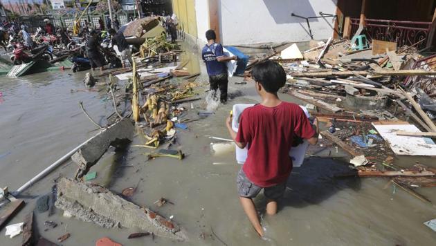 People carry items from a shopping mall badly damaged by a massive earthquake and tsunami in Palu, Central Sulawesi, Indonesia.(AP Photo)